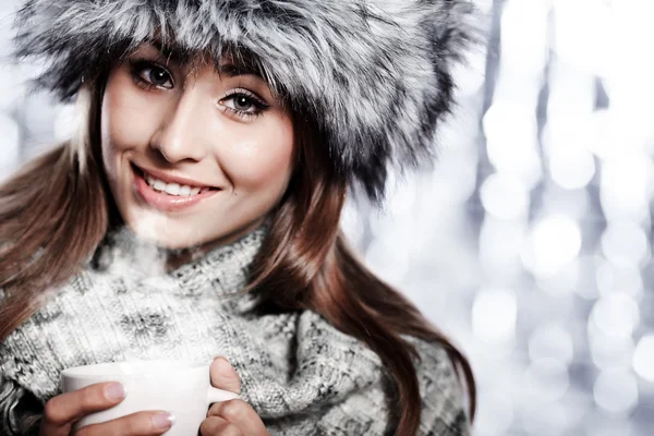 Girl blowing on hot drink dressed in winter clothing — Stock Photo, Image