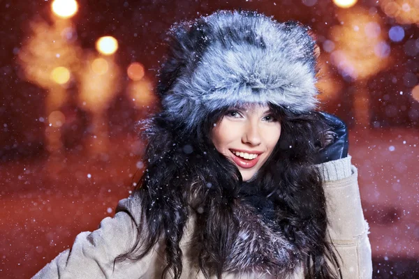 Donna sorridente nella città di notte d'inverno, sfondo neve — Foto Stock
