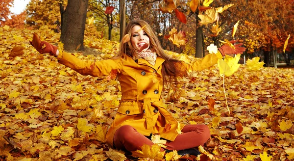 Retrato de uma mulher de outono deitada sobre folhas e sorrindo — Fotografia de Stock