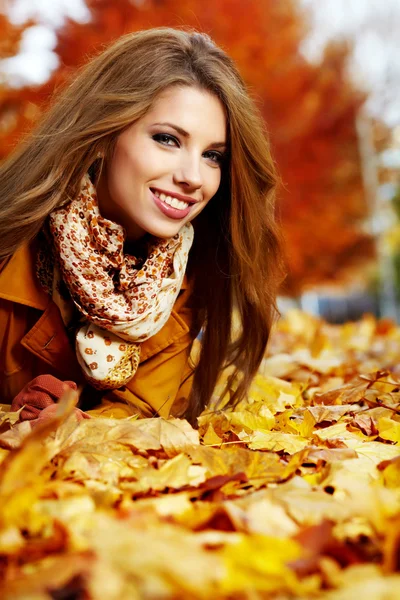葉の上に横になっている笑顔秋の女性の肖像画 — ストック写真