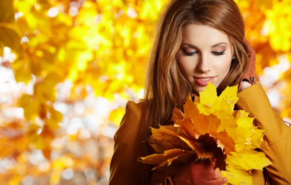 Jeune femme aux feuilles d'automne à la main et à l'automne érable jaune gar — Photo