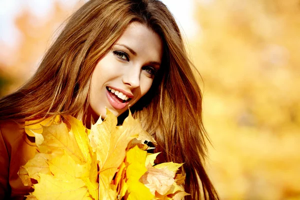 Молодая женщина с осенними листьями в руке и падение желтого кленового гара — стоковое фото