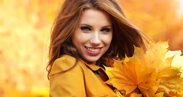 Молода жінка з осіннім листям в руці і осінньо-жовтим кленовим гардеробом — стокове фото