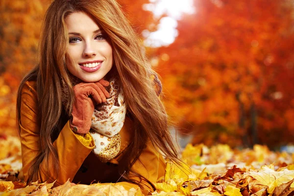 Porträtt av en höst kvinna ligger över bladen och ler — Stockfoto