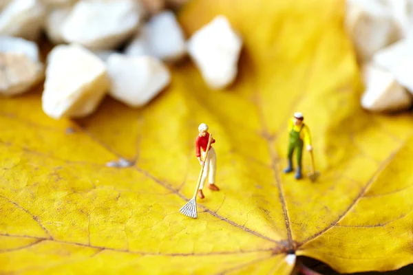 stock image Miniature figurine using a rake to clean up of the fallen leave