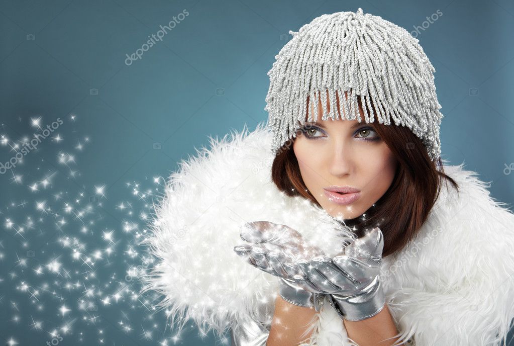 Attracive girl in santa cloth blowing snow from hands.