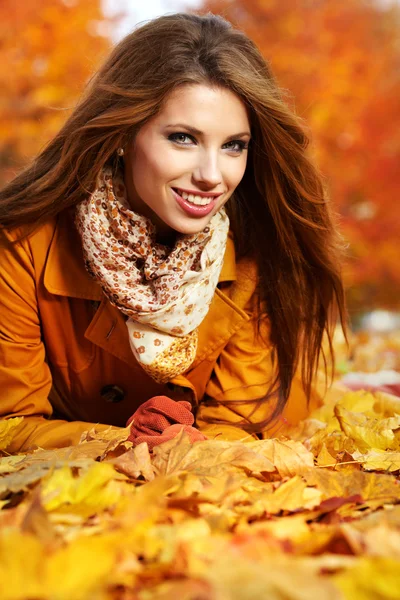 Portret van een herfst vrouw liegen over bladeren en glimlachen — Stockfoto