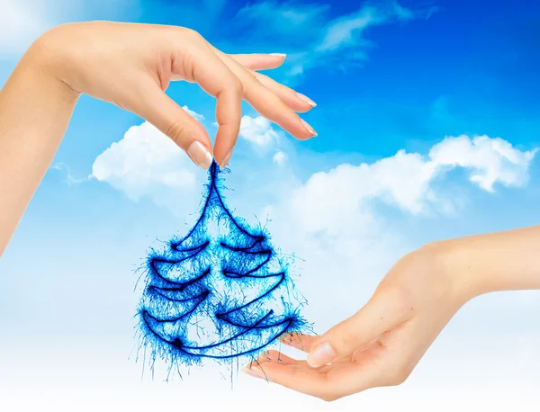 Christmas tree in hands on a blue sky — Zdjęcie stockowe