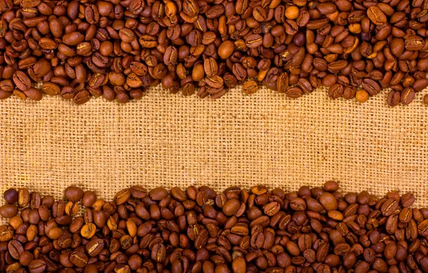 Кофе зерна на фоне мешковины — стоковое фото