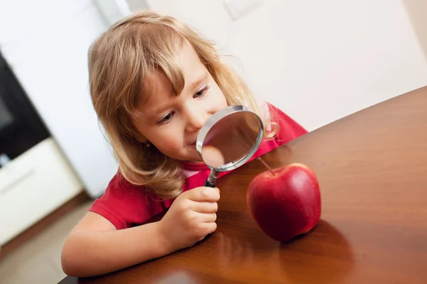 Ребенок рассматривает увеличительное стекло яблоко — стоковое фото