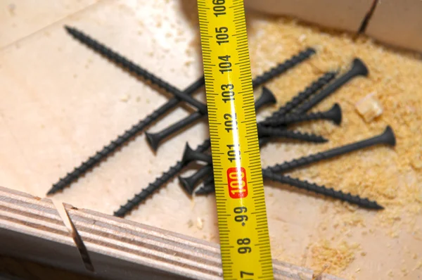 Ruban à mesurer et clou sur barre de bois — Photo