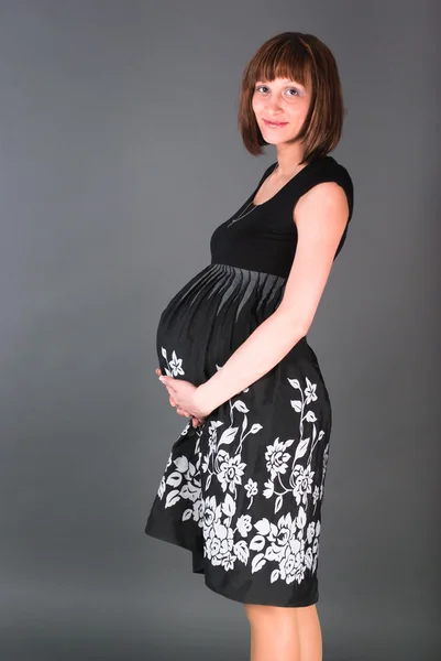 Těhotná žena v černých šatech drží pro žaludek — Stock fotografie