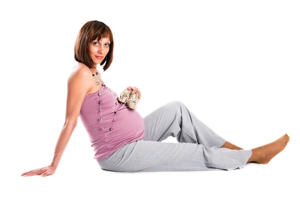 Kobieta w ciąży siedzi na podłodze, białe tło — Zdjęcie stockowe