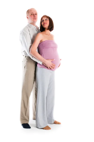 Мужчина обнимает беременную жену, белый фон — стоковое фото