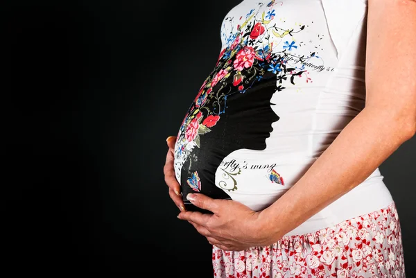 Bauch schwangere Frau auf schwarzem Hintergrund — Stockfoto