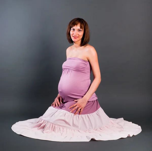 Portrét těhotné ženy na šedém pozadí — Stock fotografie