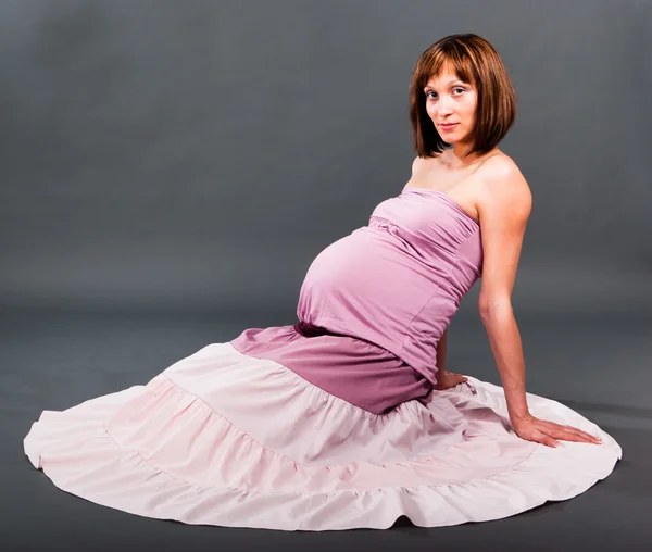 Портрет беременной женщины на сером фоне — стоковое фото
