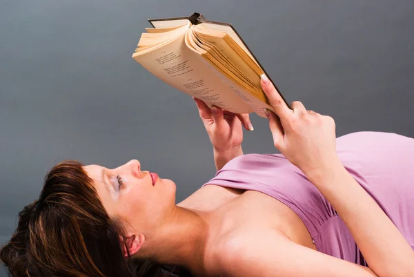 Uma mulher grávida está mentindo e lendo um livro — Fotografia de Stock