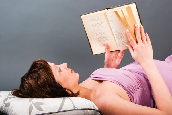 Μια έγκυος γυναίκα βρίσκεται σε ένα κρεβάτι και την ανάγνωση ενός βιβλίου — Φωτογραφία Αρχείου