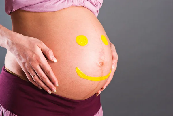 妊娠中の女性の腹部に黄色のスマイリー — ストック写真