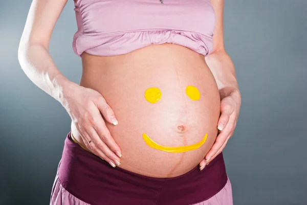 Беременная женщина с улыбкой на животе — стоковое фото