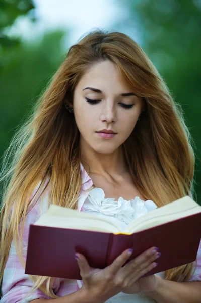 Jovem mulher lendo livro vermelho — Fotografia de Stock