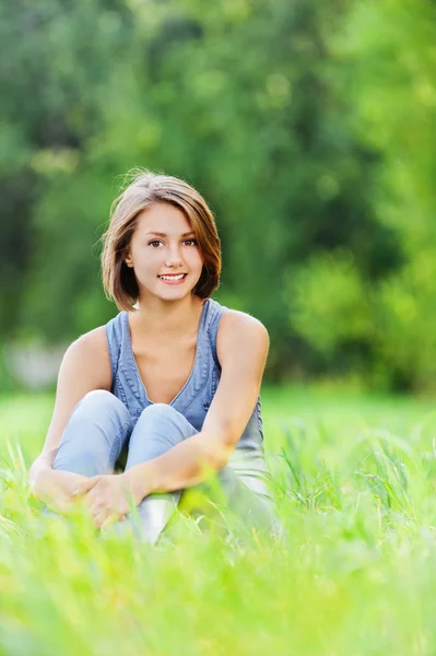 Mladá žena sedící tráva — Stock fotografie