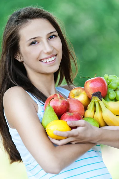 Женщина красивая владеет лотом фруктов — стоковое фото