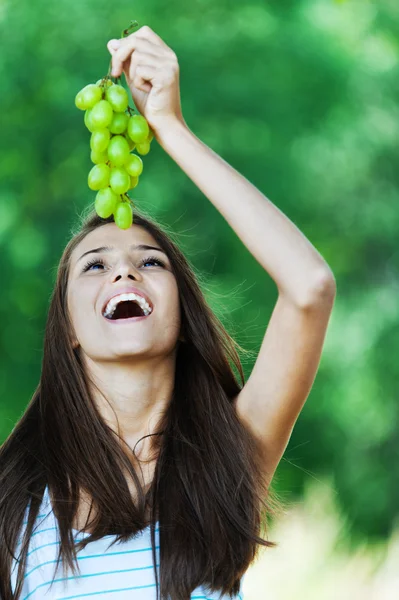 Beautiful woman holds grapes over mouth open — Stock Photo, Image