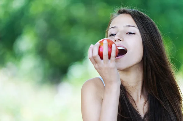 Молодая женщина кусает красное яблоко — стоковое фото