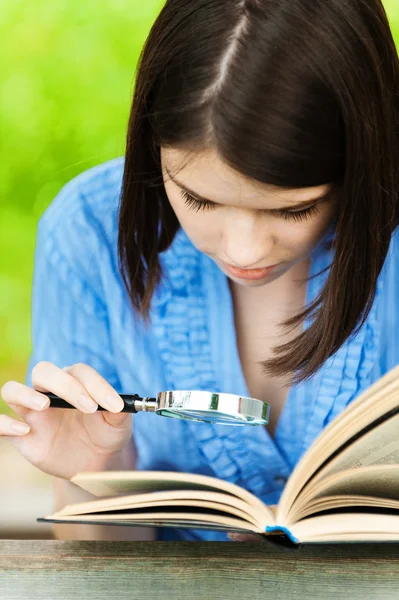 Portrait jeune femme lecture livre loupe — Photo