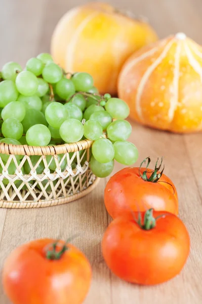 Bunch green grapes wicker basket,tomatoes,pumpkin — Stock Photo, Image