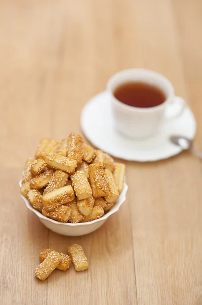 Lot cookies sprinkled sesame tasty white plate cup tea — Stock Photo, Image