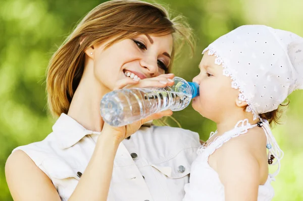 Jovem mãe carinhosa encantadora dá bebida filha — Fotografia de Stock