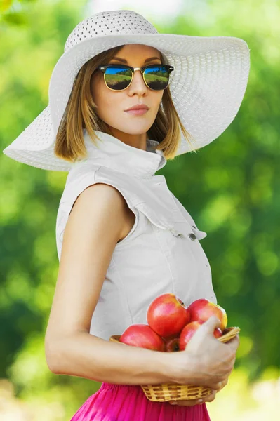 Portrait beautiful young woman serious hat holds basket apples — Stock Photo, Image