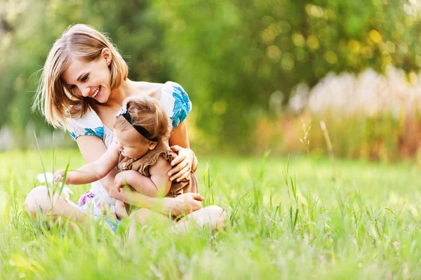 Young mother and daughter relaxing on grass — Stock Photo, Image