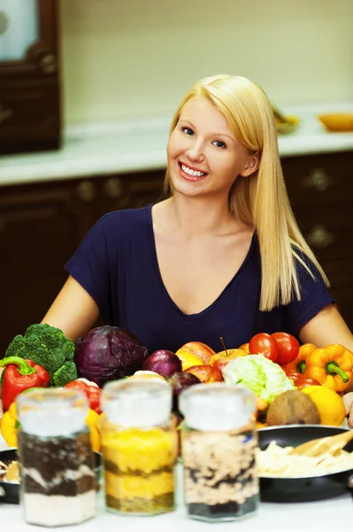 Ett porträtt av blondin på köksbordet fylld med produkter — Stockfoto