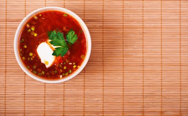 Bowl of borscht on bamboo table cloth clipart