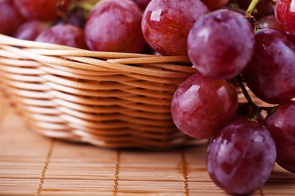 Bodegón: canasta de mimbre con uvas trenzadas — Foto de Stock
