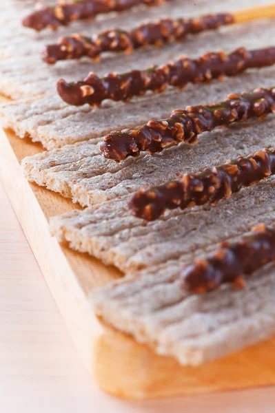 Pães e nozes torradas cristalizadas em chocolate em tábua de madeira — Fotografia de Stock