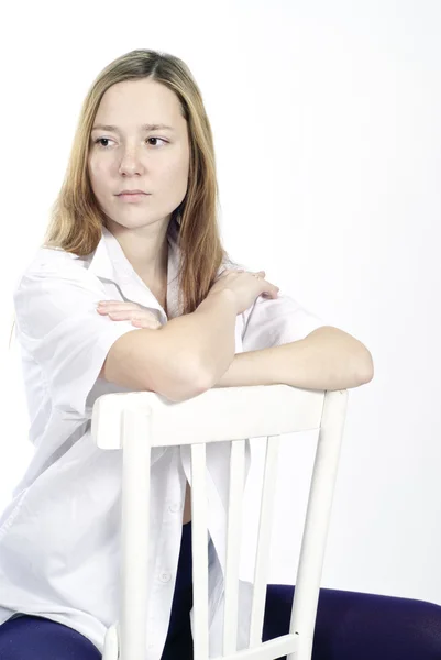 Gyönyörű fiatal nő ül egy széken — Stock Fotó