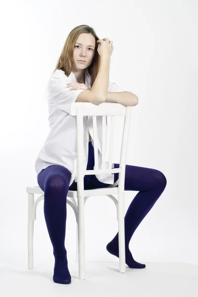 Πανέμορφη νεαρή γυναίκα που κάθεται σε μια καρέκλα — Φωτογραφία Αρχείου