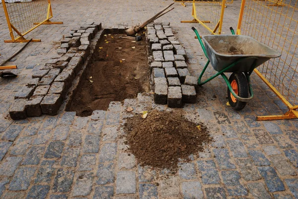 Pedras, um carrinho de mão e ferramentas para pavimentação — Fotografia de Stock