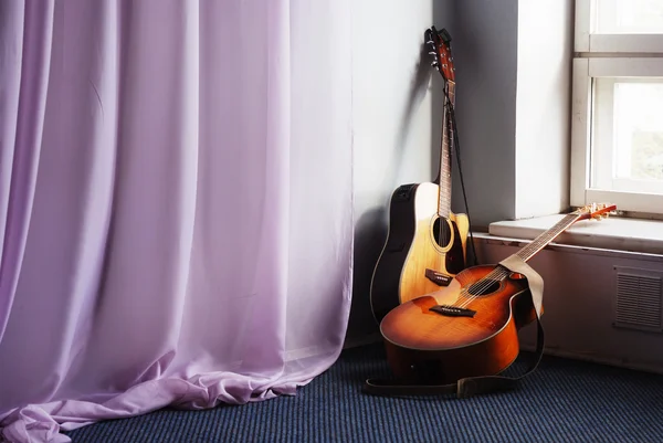 Две акустические гитары у окна — стоковое фото