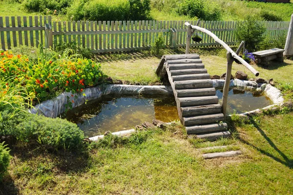 Невеликий садовий ставок з дерев'яним мостом — стокове фото