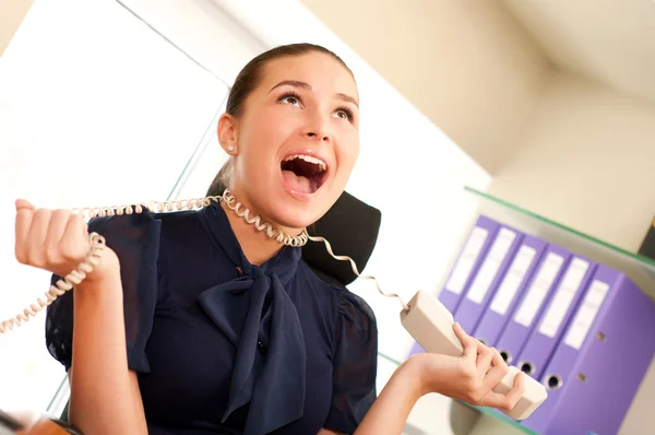 Business woman screaming in telephone receiver — Stock Photo, Image