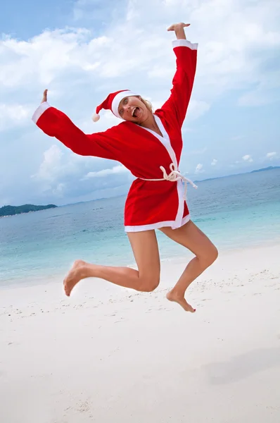 Jonge vrouw op het strand in santa's kostuum — Stockfoto