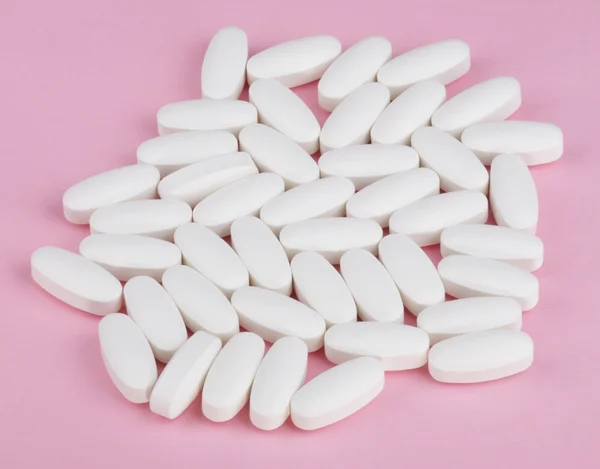Píldora blanca sobre fondo rosa — Foto de Stock