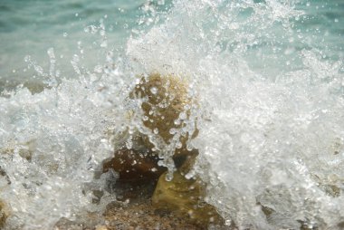 dalgalar ve deniz köpüğü kayalarda.