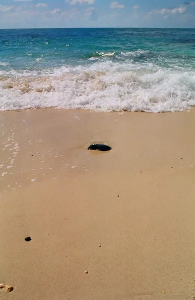 それの後ろに波と砂の石します。. — ストック写真